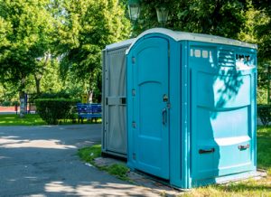 ada compliant porta potty in a park next to a walk way